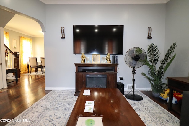 living room featuring arched walkways, wood finished floors, and baseboards