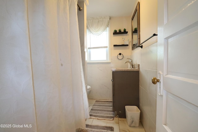bathroom featuring vanity, toilet, and tile walls