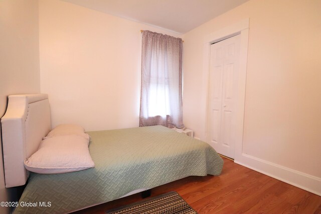 bedroom featuring wood finished floors, baseboards, and a closet