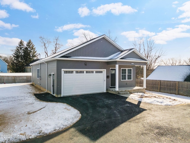 exterior space featuring covered porch, fence, a garage, and aphalt driveway