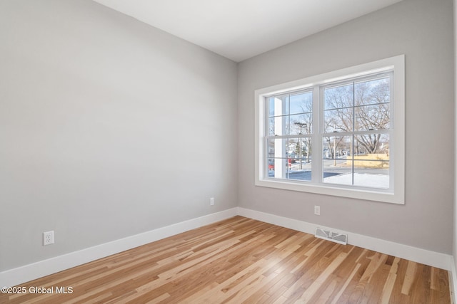 spare room with baseboards, visible vents, and wood finished floors