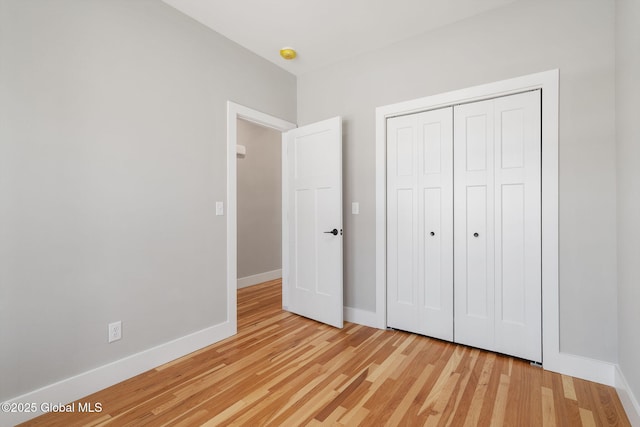 unfurnished bedroom with light wood finished floors, baseboards, and a closet