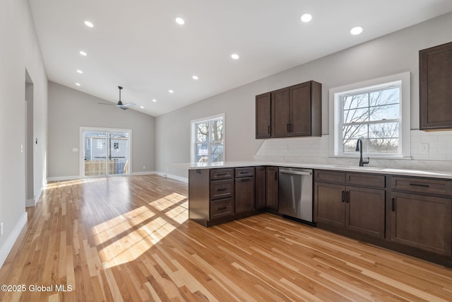 kitchen featuring a sink, a peninsula, tasteful backsplash, dishwasher, and light wood-style flooring