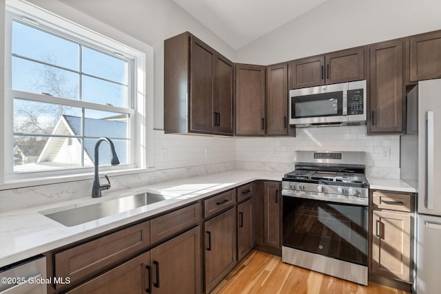 kitchen featuring a healthy amount of sunlight, appliances with stainless steel finishes, a sink, and vaulted ceiling