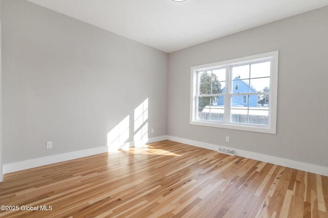 spare room featuring light wood-type flooring, visible vents, and baseboards