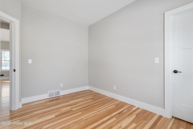 spare room featuring baseboards, visible vents, and wood finished floors