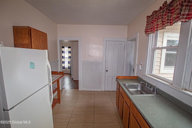 27 Kingsboro Ave, Gloversville, NY 12078 - kitchen featuring freestanding refrigerator, brown cabinets, light tile patterned floors, and a sink