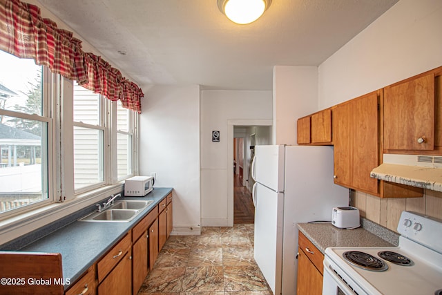 27 Kingsboro Ave, Gloversville, NY 12078 - kitchen featuring under cabinet range hood, brown cabinetry, white appliances, and a sink