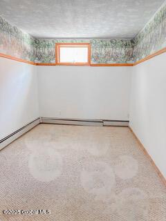 carpeted empty room with wallpapered walls and baseboards