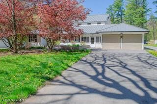 view of front of property with an attached garage, driveway, metal roof, and a standing seam roof