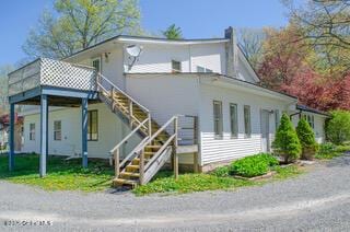 rear view of property featuring stairway and a chimney