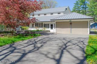 view of front of house with metal roof, driveway, a garage, and a standing seam roof