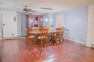 dining area with a baseboard heating unit, wood finished floors, baseboards, and ceiling fan
