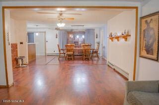 dining area with baseboards, a baseboard radiator, and wood finished floors