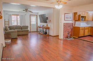 living room with baseboards, a ceiling fan, and wood finished floors