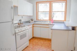 kitchen featuring white appliances, light countertops, a peninsula, and a sink