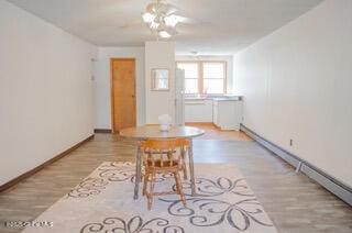 unfurnished dining area with wood finished floors, baseboards, and a baseboard heating unit