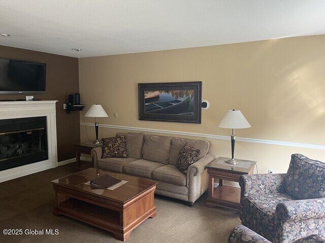 living room with a glass covered fireplace and carpet