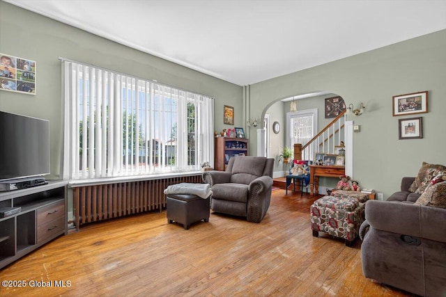5 Hillview Ave, East Greenbush, NY 12144 - living area with radiator heating unit, arched walkways, light wood-style floors, and stairs