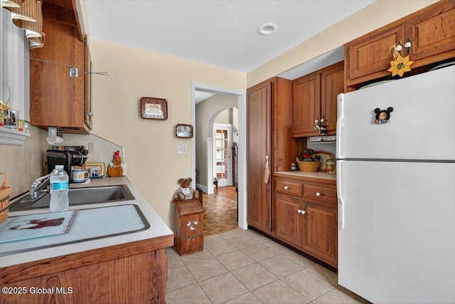 5 Hillview Ave, East Greenbush, NY 12144 - kitchen with freestanding refrigerator, arched walkways, brown cabinetry, light countertops, and light tile patterned floors