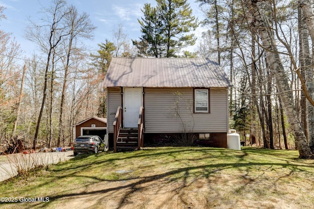 exterior space with a lawn, an outbuilding, metal roof, a garage, and entry steps
