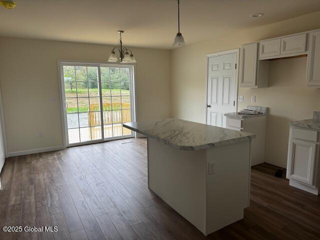 kitchen with light stone countertops, white cabinetry, a center island, and dark wood finished floors