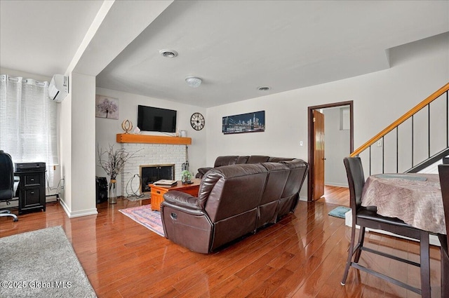 1576 State St, Schenectady, NY 12304 - living room with wood finished floors, a wall unit AC, a fireplace, an office area, and stairway