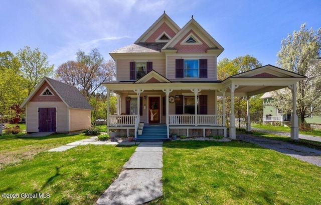 victorian home featuring a front lawn, an outdoor structure, and a porch