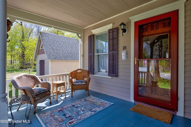 entrance to property with covered porch and roof with shingles