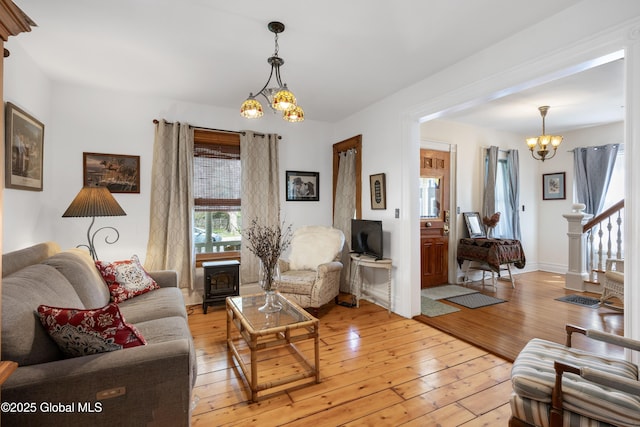 living area featuring a chandelier, light wood-style floors, and stairs
