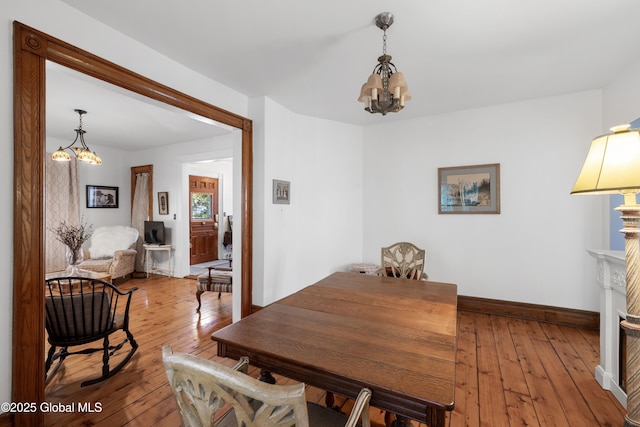 dining room with a chandelier, hardwood / wood-style flooring, and baseboards