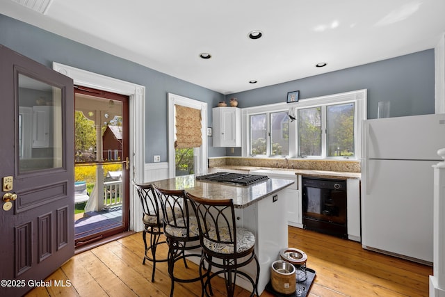 kitchen featuring freestanding refrigerator, white cabinets, gas cooktop, light wood-type flooring, and recessed lighting