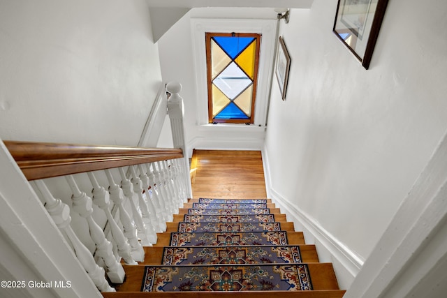 stairway with wood-type flooring and baseboards