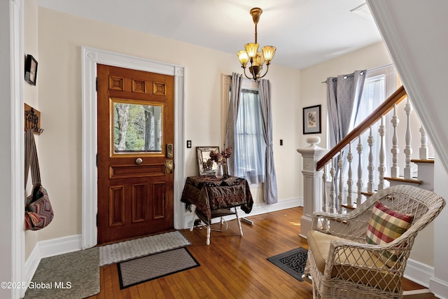 entryway featuring a chandelier, hardwood / wood-style flooring, stairs, and baseboards
