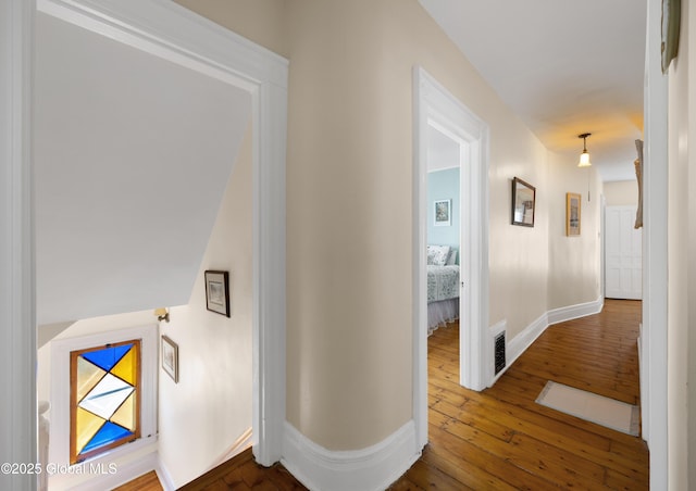 corridor featuring dark wood-type flooring and baseboards