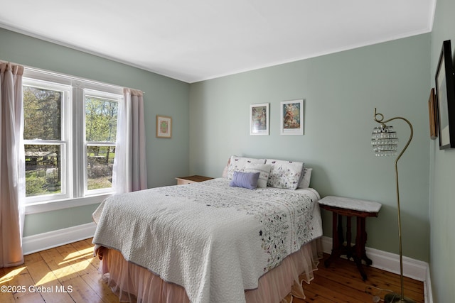 bedroom featuring baseboards, hardwood / wood-style flooring, and ornamental molding