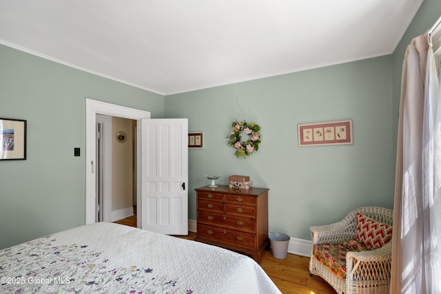 bedroom with wood finished floors, baseboards, and crown molding