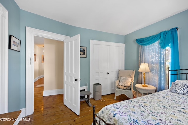 bedroom with wood-type flooring, a closet, and baseboards