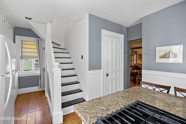 stairway with wainscoting, wood-type flooring, and baseboards