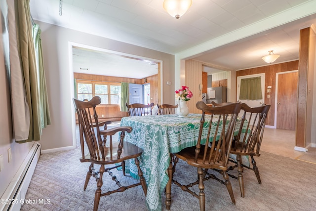 188 Fort Edward Rd, Moreau, NY 12828 - dining room featuring a baseboard heating unit, light carpet, baseboards, and wood walls