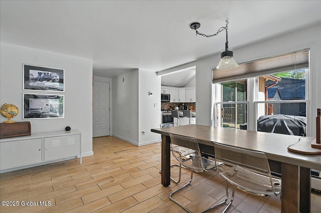 dining space featuring light wood-style flooring and baseboards