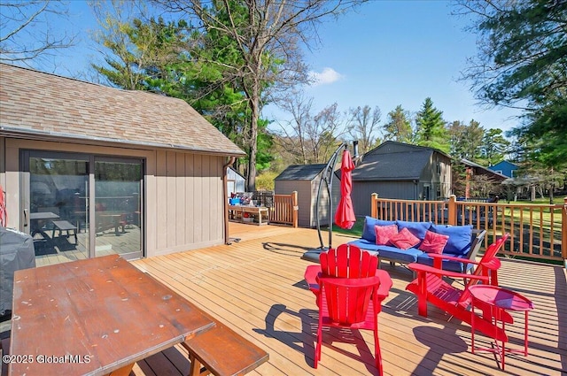 wooden deck featuring outdoor dining area, a storage shed, an outbuilding, and an outdoor hangout area