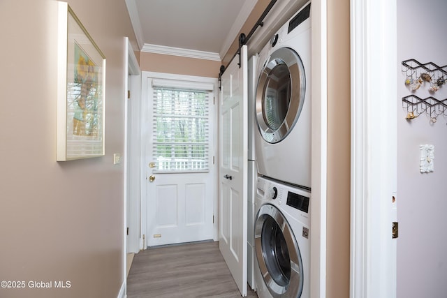 laundry area with estacked washer and dryer, a barn door, crown molding, and light wood finished floors