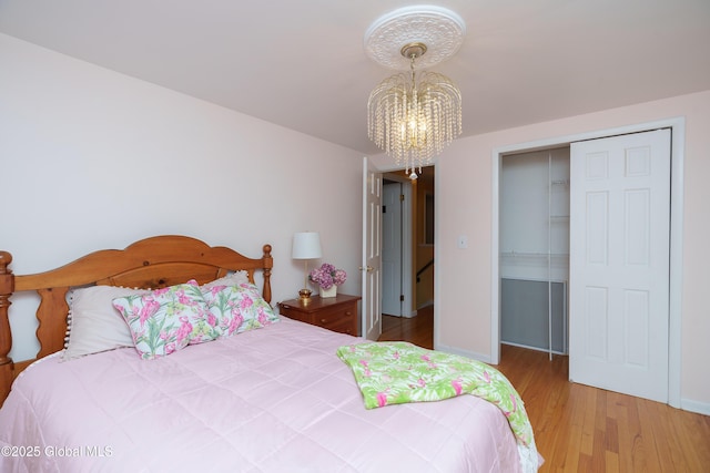 bedroom featuring a closet, a chandelier, wood finished floors, and baseboards