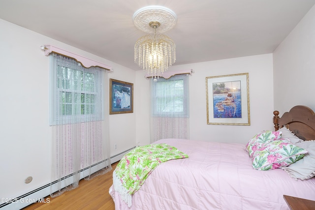 bedroom featuring a baseboard heating unit, a chandelier, and wood finished floors