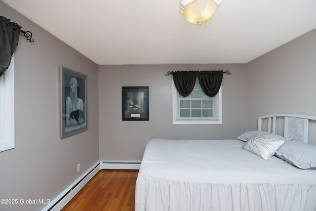 bedroom with a baseboard heating unit, a baseboard radiator, wood finished floors, and baseboards