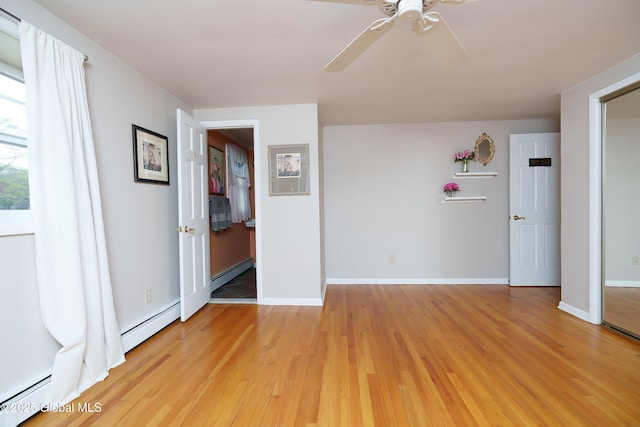 empty room featuring baseboard heating, a baseboard heating unit, ceiling fan, and light wood-type flooring