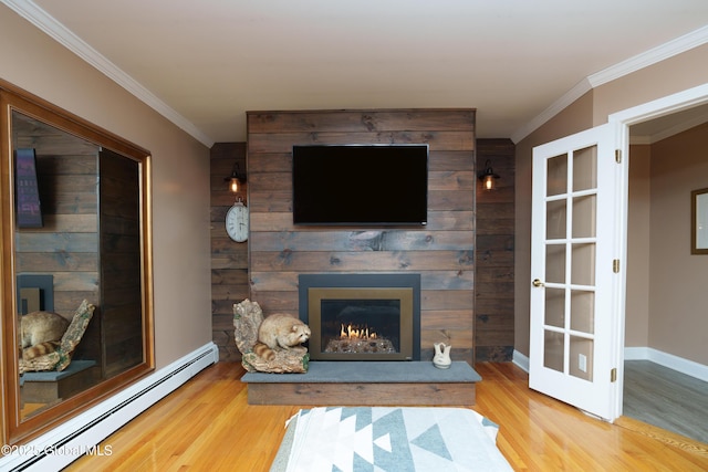 living area featuring a baseboard heating unit, wood finished floors, a fireplace, ornamental molding, and baseboards