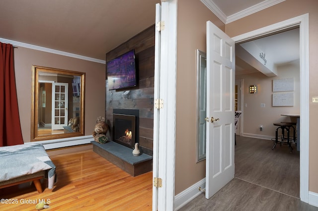 living room featuring ornamental molding, wood finished floors, a baseboard radiator, a fireplace, and baseboards