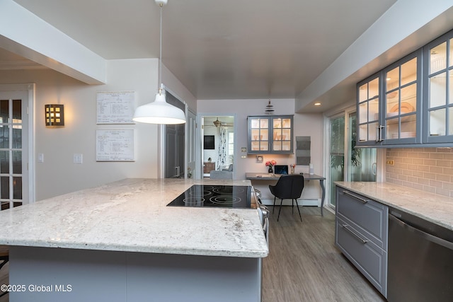 kitchen with dishwasher, wood finished floors, light stone countertops, gray cabinets, and glass insert cabinets
